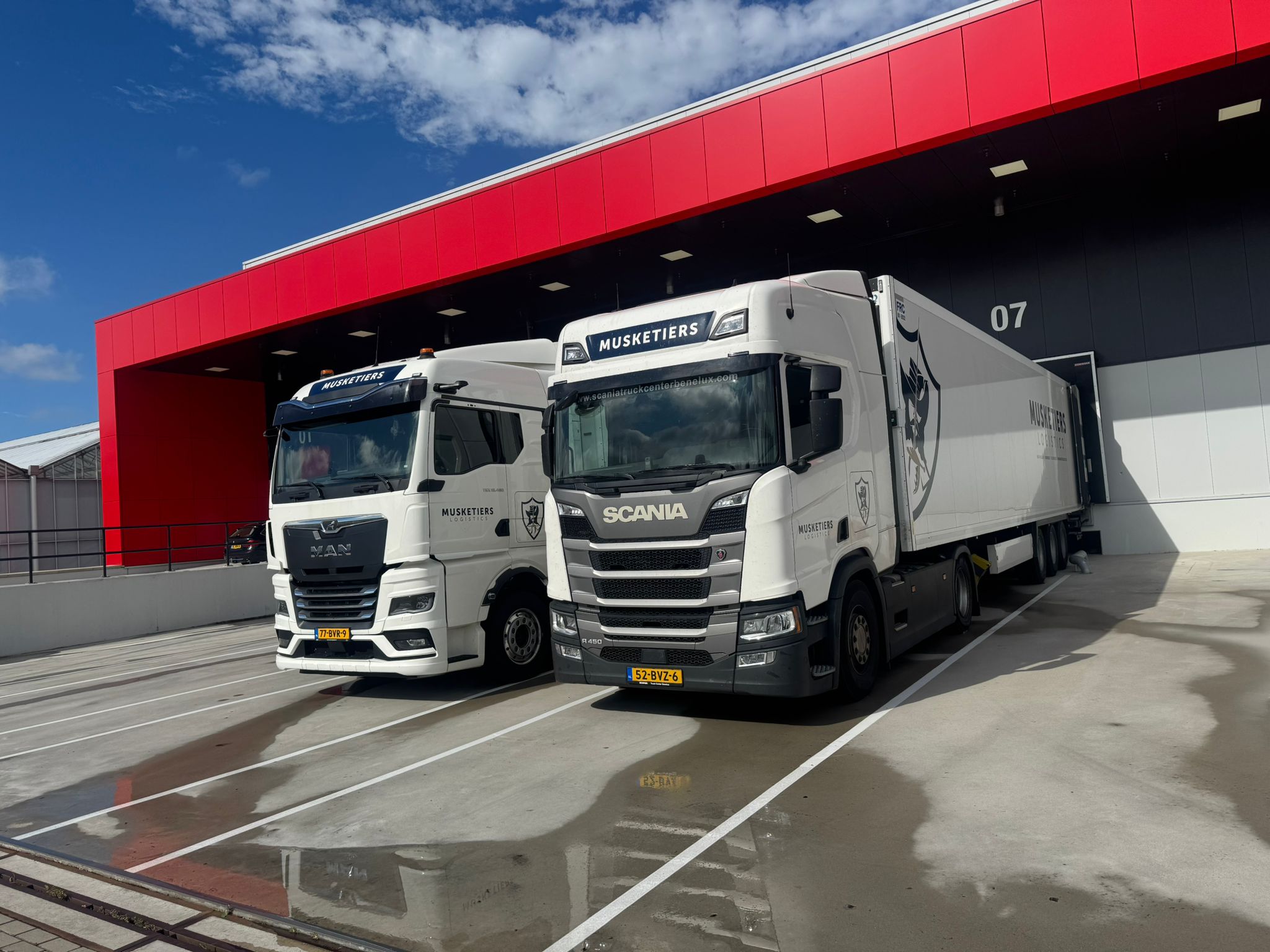 Twee vrachtwagens van Musketiers Logistics aan het dock